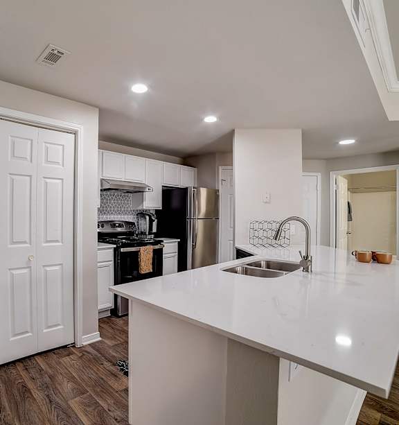 A kitchen with white cabinets and a white island.