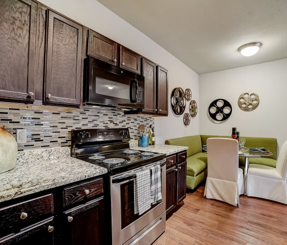 a kitchen with a stove top oven next to a table with a green couch in the background