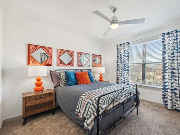 A bedroom with a bed, a ceiling fan, and a window with curtains.
