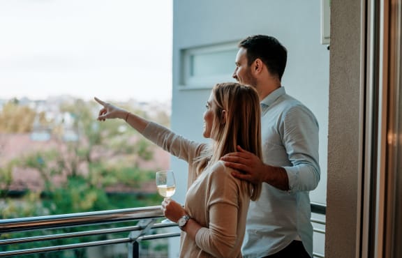 a man and woman standing on a balcony holding a glass of wine and looking out at The Woods, Kanata, Ottawa, ON