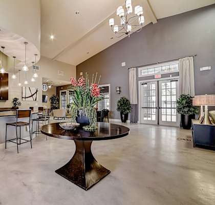 a large living room with a large chandelier and a round table with a vase