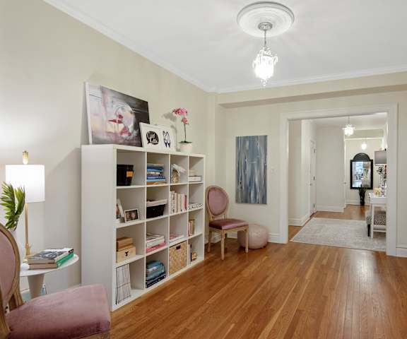 A room with a wooden floor and a white wall with a painting hanging on it.