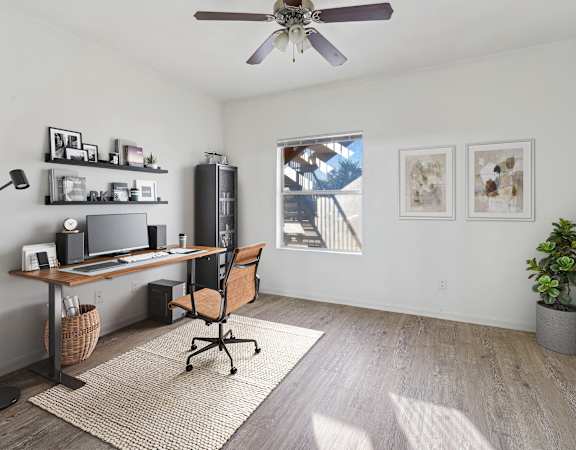 Stylish home office with a modern wood desk, sleek shelving, and natural light.