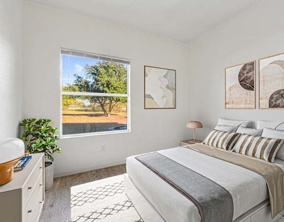 Bright and modern bedroom with neutral tones, stylish decor, and a scenic view.