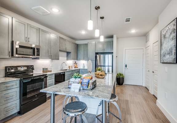 A modern kitchen with a table and chairs in the middle.