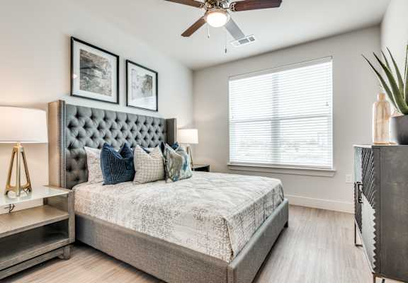 A bedroom with a large bed and a ceiling fan.