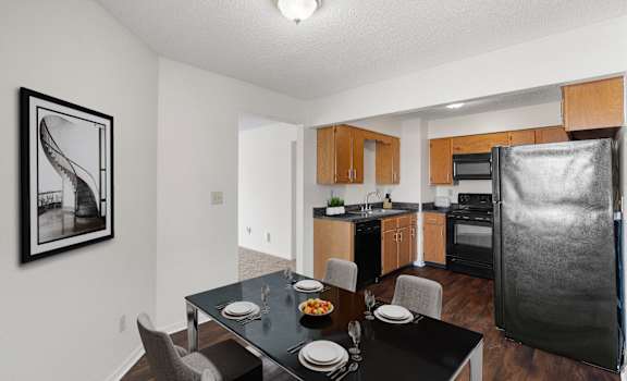 our apartments offer a kitchen and dining area with a black table and chairs