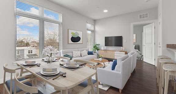 A dining room with a table set for six and a couch with a blue pillow.