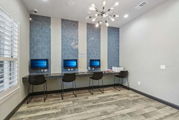 A room with a desk and chairs with a computer on it.