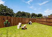 Thumbnail 4 of 6 - A backyard with a wooden fence and a white chair.