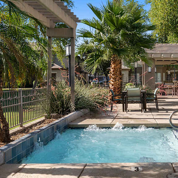 A pool with a waterfall and a hot tub in a backyard.