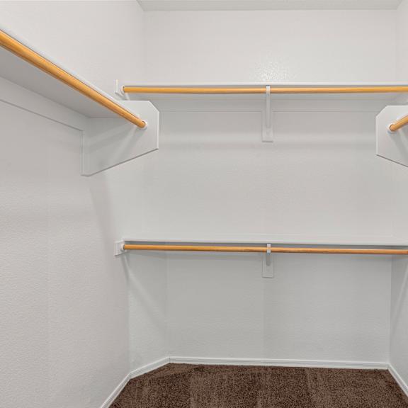 A white closet with two shelves and a carpeted floor.