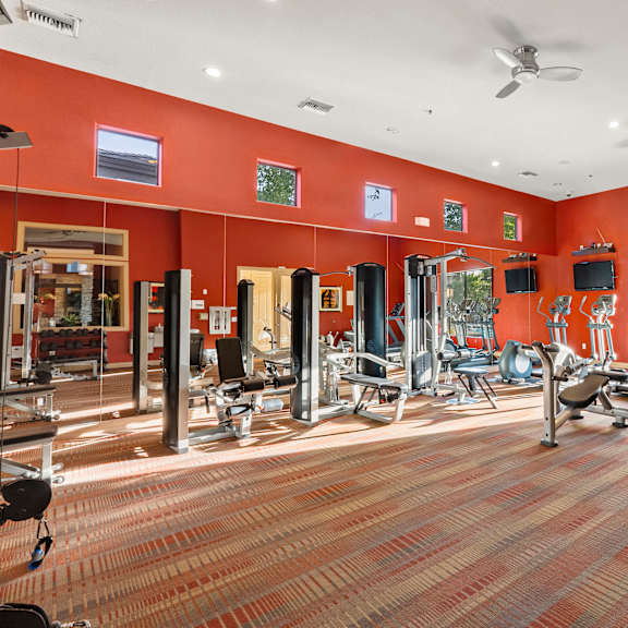A gym with a variety of equipment including treadmills, weights, and exercise machines.