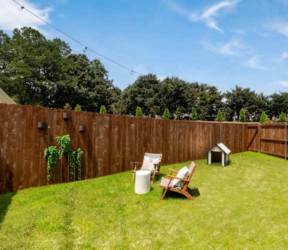 A backyard with a wooden fence and a white chair.