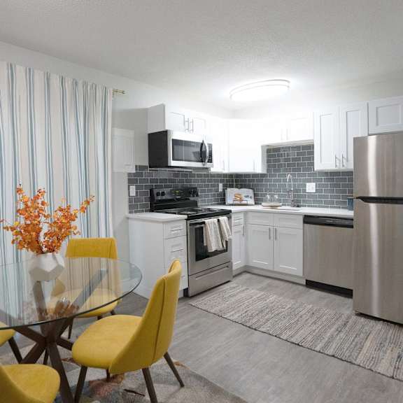 A modern kitchen with a glass table and yellow chairs.
