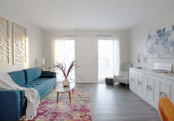 A blue couch is in front of a white wall with a painting on it.