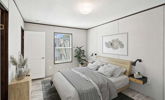 A bedroom with a bed, nightstand, and a window  at Converse Meadows MHC in Converse, TX
