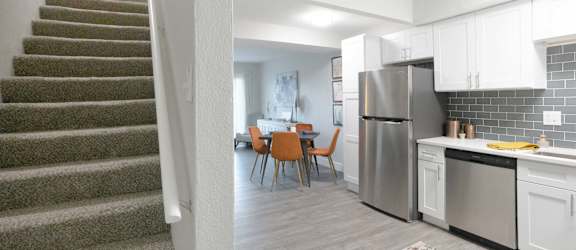 A kitchen with a staircase on the left side.