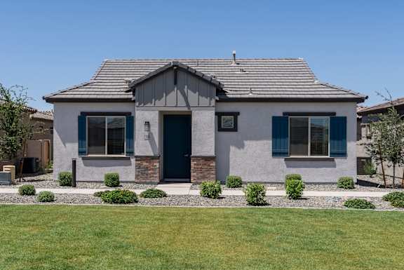 A house with a grey facade and a dark blue door.