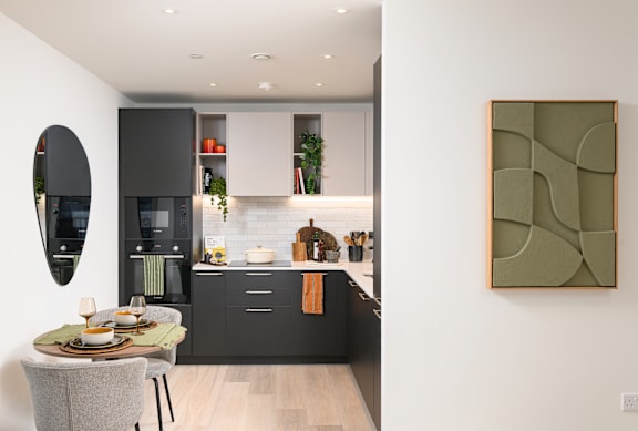 A modern kitchen with a dining table and a painting on the wall.