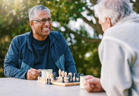 Two people playing chess outdoors.