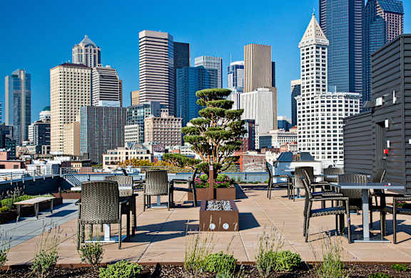 a roof deck with tables and chairs and a view of the city