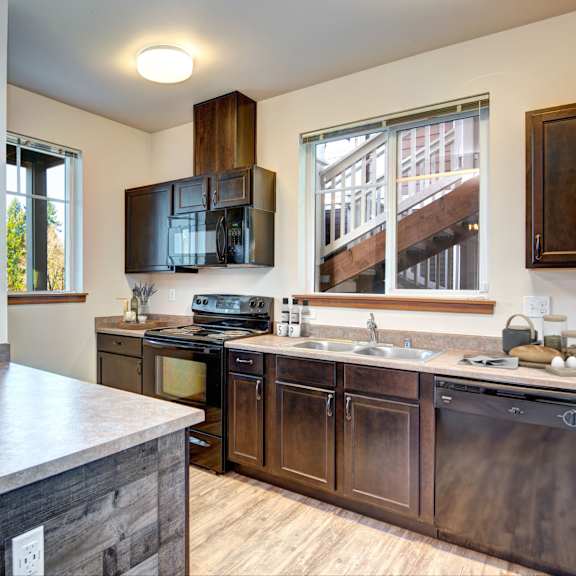 A kitchen with brown cabinets and a marble countertop.