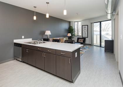 A modern kitchen with a large island and a dining area in the background.