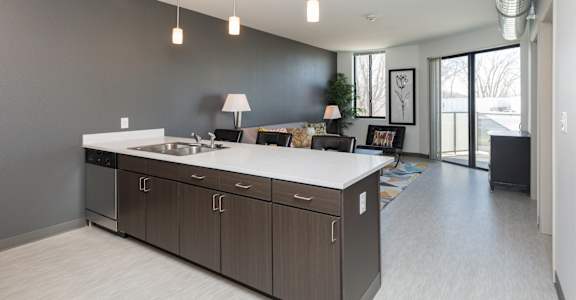 A modern kitchen with a large island and a dining area in the background.