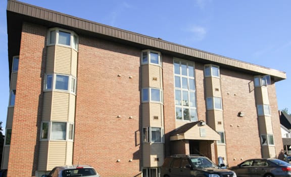 A car is parked in front of a brick building.