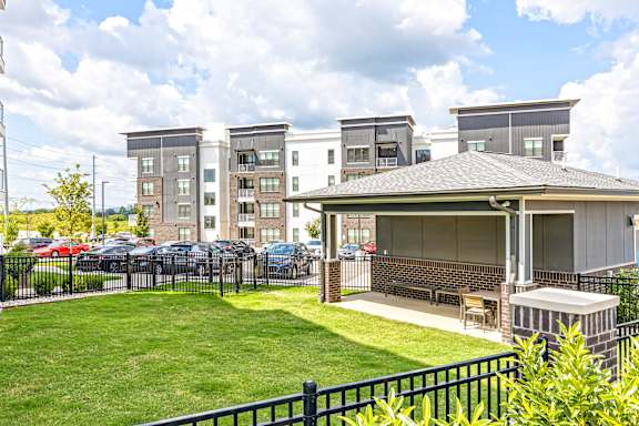 A building with a black fence and a green lawn in front.