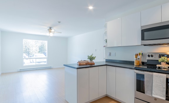 A kitchen with white cabinets and a wooden floor.