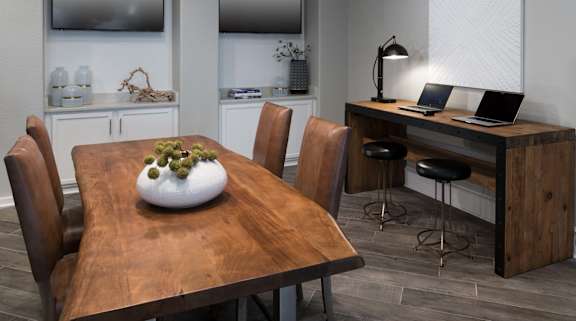 A wooden dining table with a bowl of grapes in the center and chairs around it.