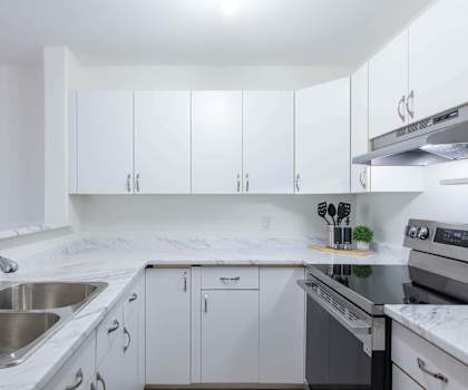 A kitchen with white cabinets and a marble countertop.