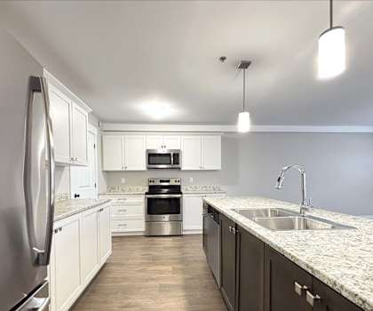 A modern kitchen with a stainless steel refrigerator and a marble countertop.