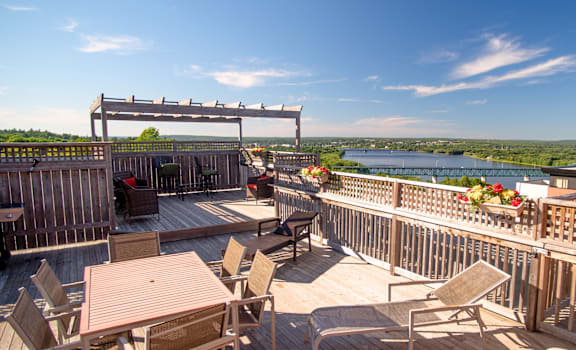A wooden deck with a table and chairs overlooking a river.