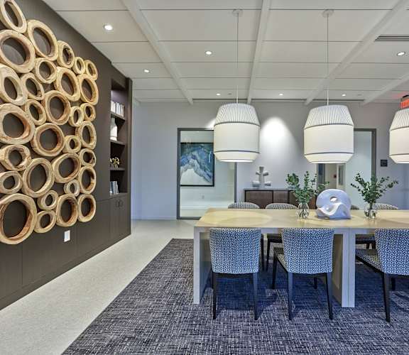 a conference room with a large table and chairs with three large pendants hanging from the ceiling