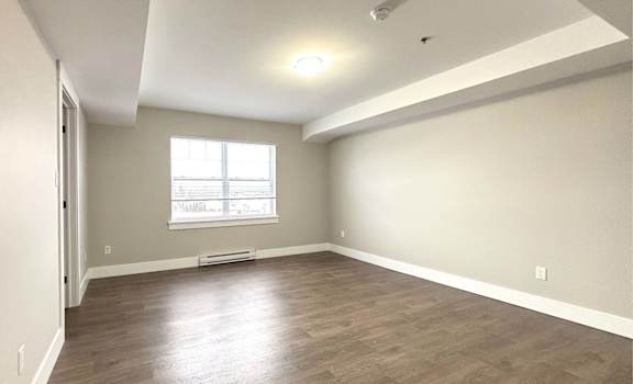 A room with a window and wooden flooring.