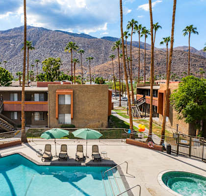 A pool surrounded by palm trees and a mountain in the background.