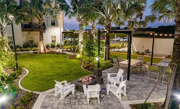 a patio with chairs and palm trees at night