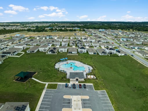 an aerial view of a large housing complex with a pool and grassy area