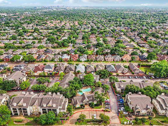A bird's eye view of a suburban neighborhood with houses and a pool.