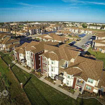 A bird's eye view of a residential area with houses and a parking lot.