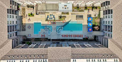 A top-down view of a building with a pool and a large open area with people sitting on chairs.