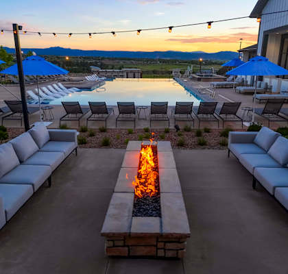 a lounge area with couches and chairs around a fire pit
