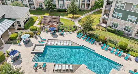 A large swimming pool surrounded by lounge chairs and umbrellas.at North Creek, Hutto, TX, 78634