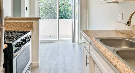 A kitchen with a stove, sink, and a ceiling fan.