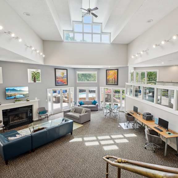A spacious room with a fireplace, couches, and a ceiling fan.