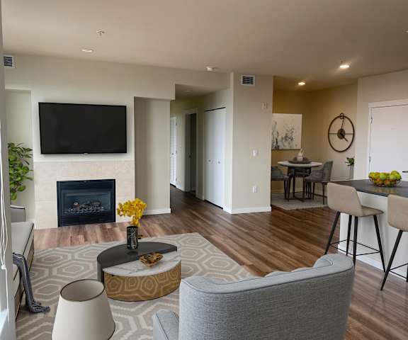 a living room with a fireplace and a dining room in the background