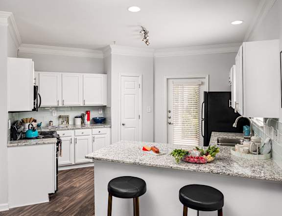 a kitchen with white cabinets and a counter top with black appliances
